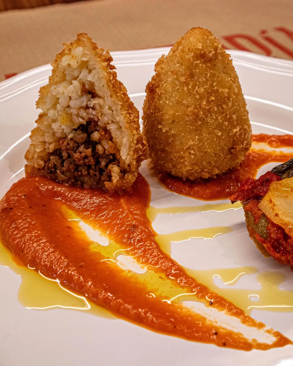 Arancino siciliano abierto, relleno de carne, con salsa de tomate