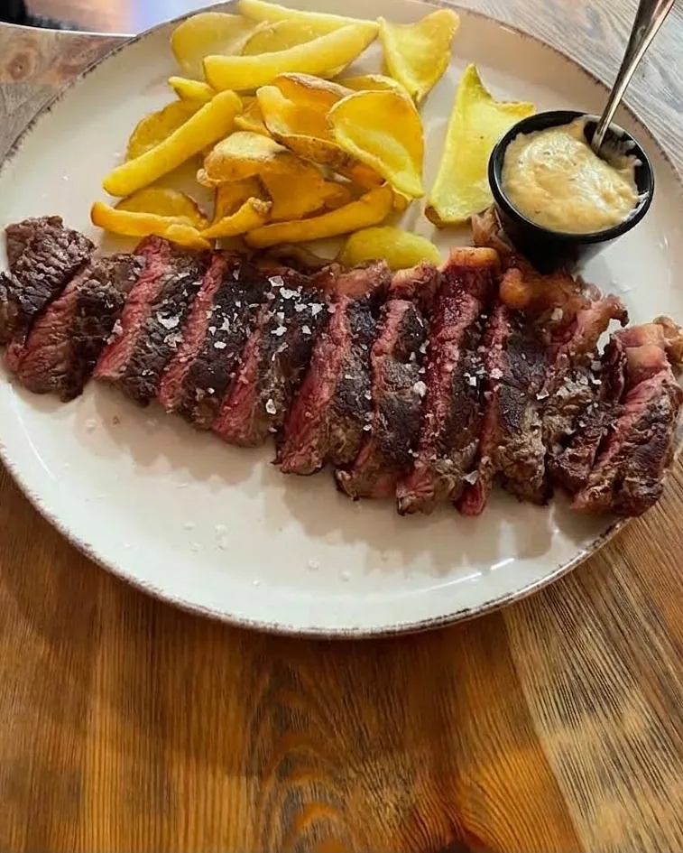 Entrecot de carne madurada en lonchas con patatas fritas y salsa de mantequilla Café de París
