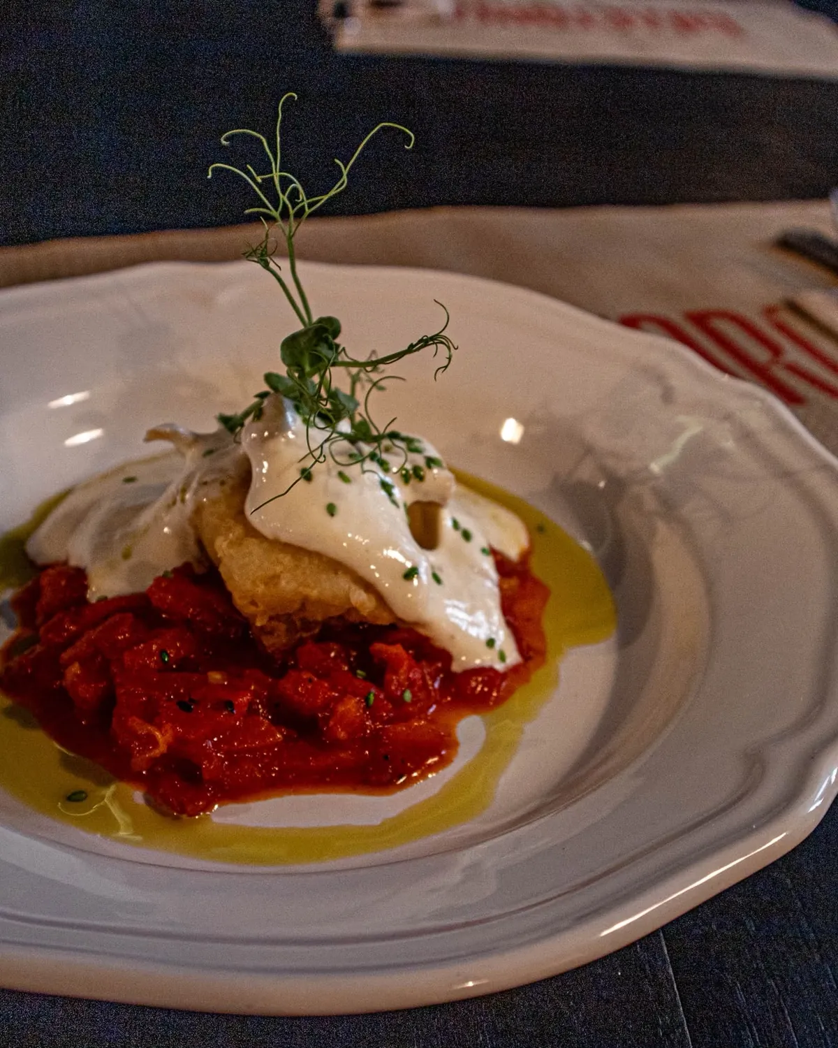 Bacalao sobre asadillo de pimientos con espuma de alioli y brotes de guisante